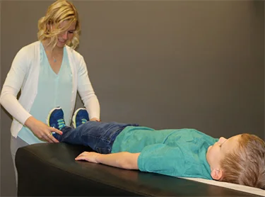 Chiropractor Waukee IA Kelsey Pettitt Our Activator Chiropractic Method Child Dr. Kelsey Pettitt performing their activator chiropractic method on a child.