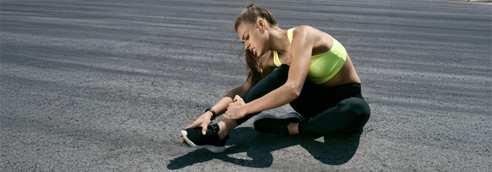Chiropractic Waukee IA Ankle Injury A woman holding her ankle in pain.