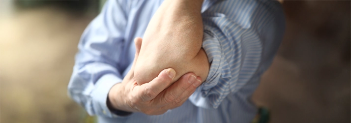 Chiropractic Waukee IA Elbow Pain A person holding their elbow in pain.