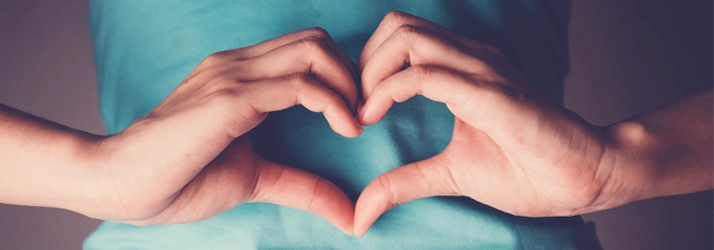 Chiropractic Waukee IA Heart Hands Person making heart hands over their stomach.