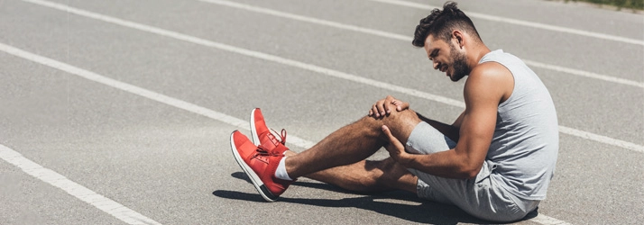 Chiropractic Waukee IA Knee Pain Track Runner Injury A man holding his leg in pain.