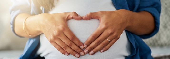 Chiropractic Waukee IA Pregnancy Pregnant woman with heart hands over her belly.