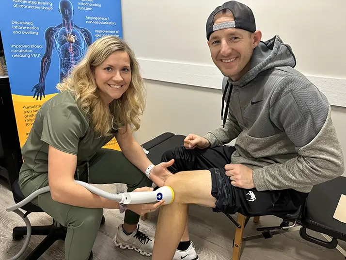Chiropractor Waukee IA Kelsey Pettitt With Softwave Patient 1 Chiropractor Kelsey Pettitt with a SoftWave patient.