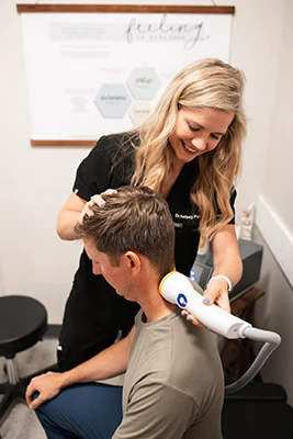 Chiropractor Waukee IA Kelsey Pettitt With Softwave Patient Neck Chiropractor Kelsey Pettitt performing SoftWave therapy on a patients neck.